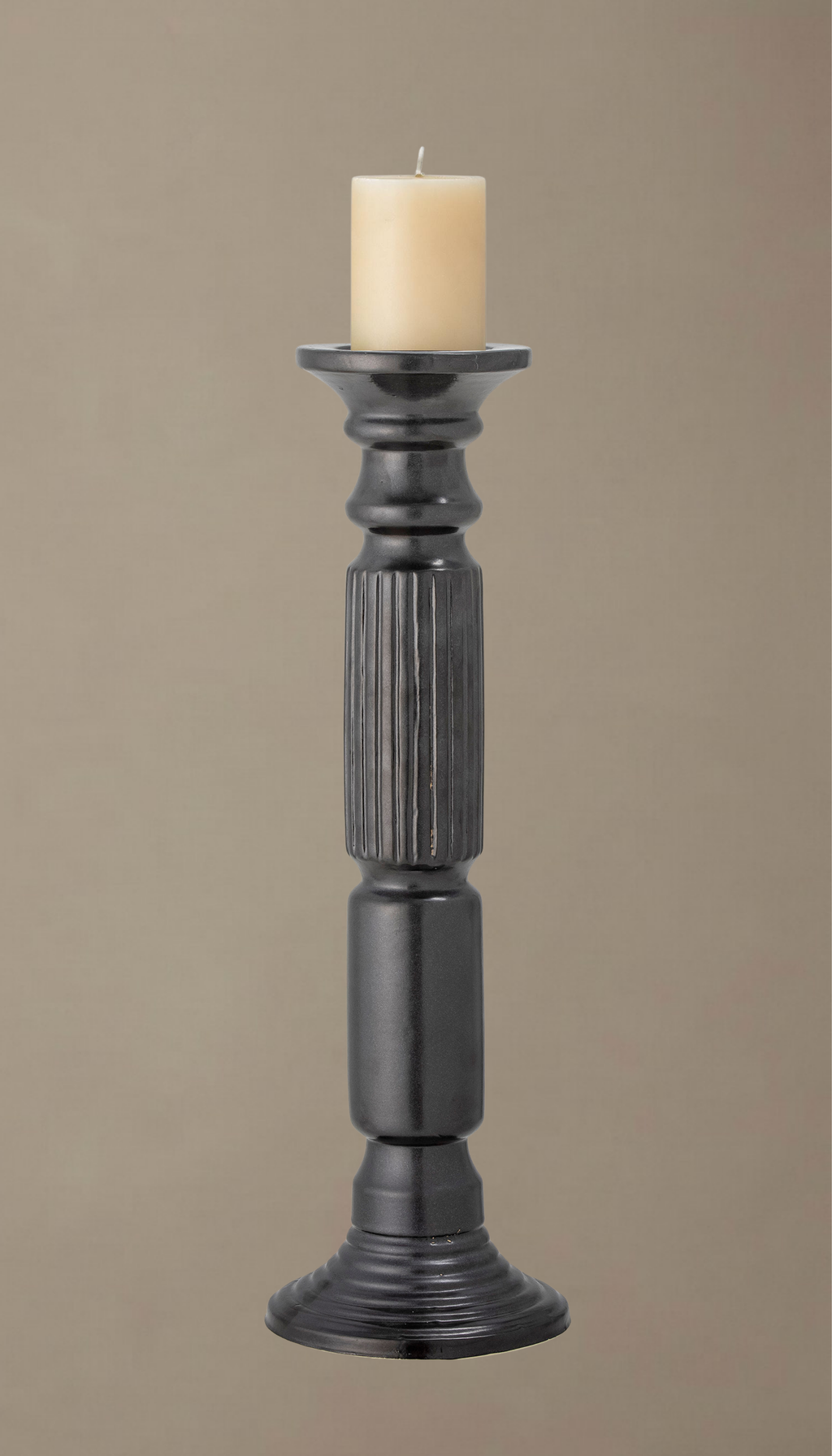 Candelabro alto de cerámica modelo Laurel en color negro satinado, con diseño torneado clásico y sección central estriada, sosteniendo una vela de pilar color crema.