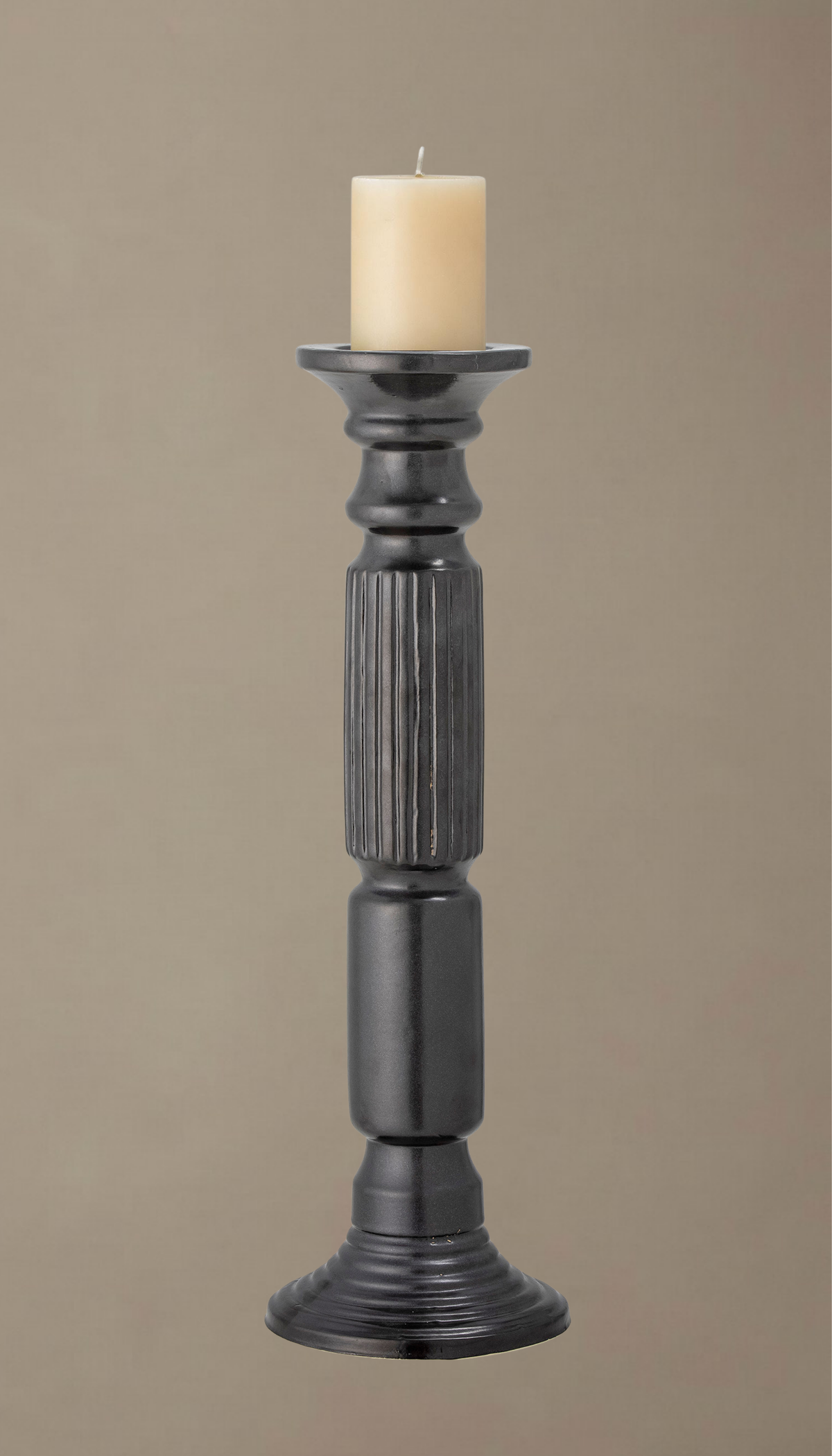 Candelabro alto de cerámica modelo Laurel en color negro satinado, con diseño torneado clásico y sección central estriada, sosteniendo una vela de pilar color crema.