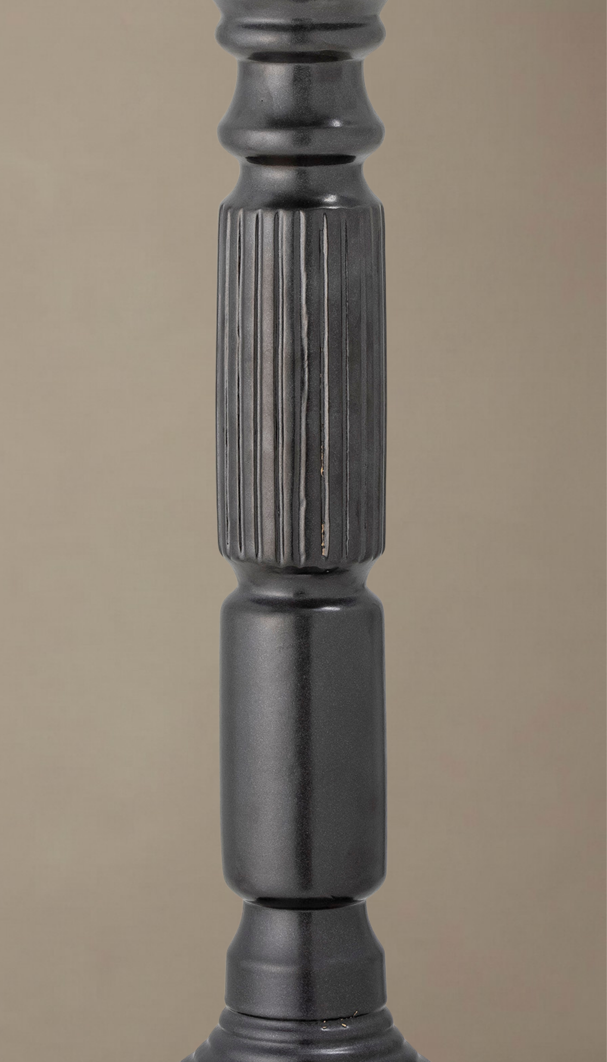 Candelabro alto de cerámica modelo Laurel en color negro satinado, con diseño torneado clásico y sección central estriada, sosteniendo una vela de pilar color crema.