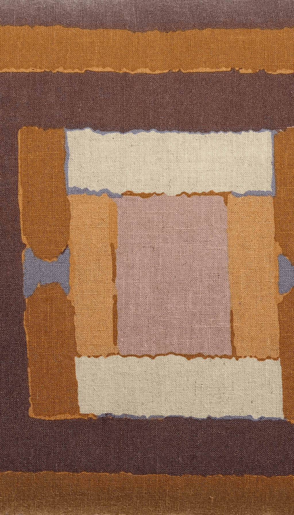 Cojín rectangular modelo Brezo con diseño de estampado geométrico en bloques combinando colores tierra, terracota, marrón y rosa sobre un fondo claro natural.