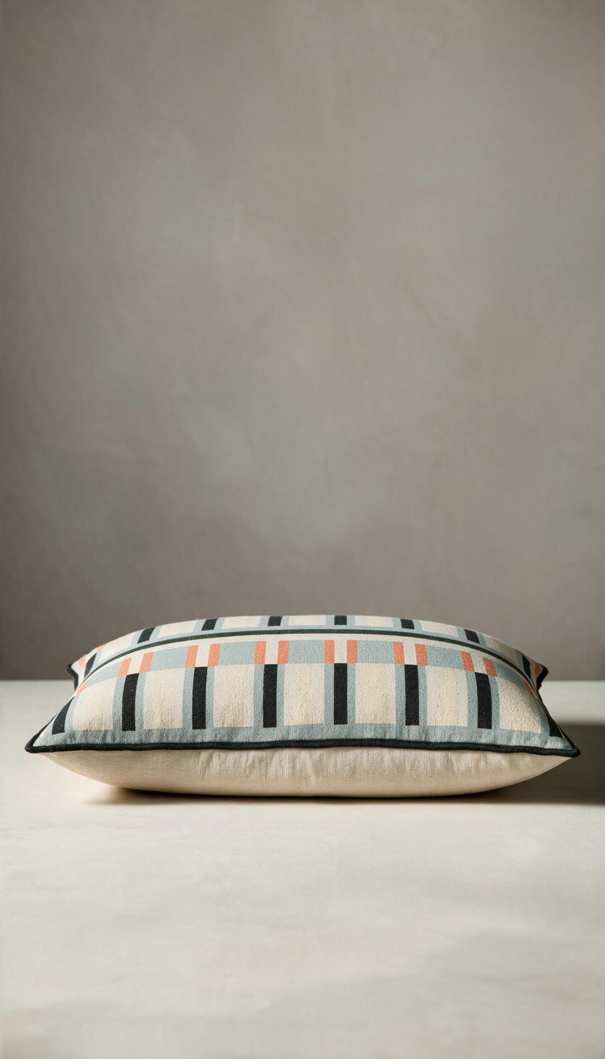 Cojín rectangular lumbar modelo Jalisco con estampado geométrico de rayas en tonos azul menta, crema, naranja y negro, rematado con un ribete perimetral oscuro.
