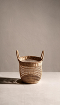 Cesta organizadora modelo Priego elaborada en fibras naturales con un diseño de trenzado abierto calado y dos asas superiores, proyectando una sombra sobre fondo neutro.