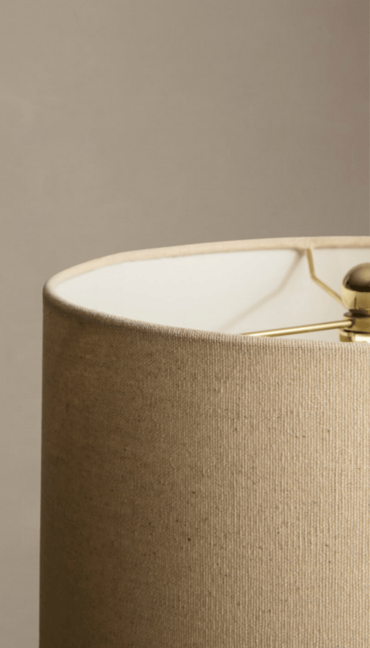 Lámpara de mesa modelo Umbral con base escultural tipo ánfora en gris texturizado efecto piedra, y pantalla cilíndrica de tela de lino color natural.