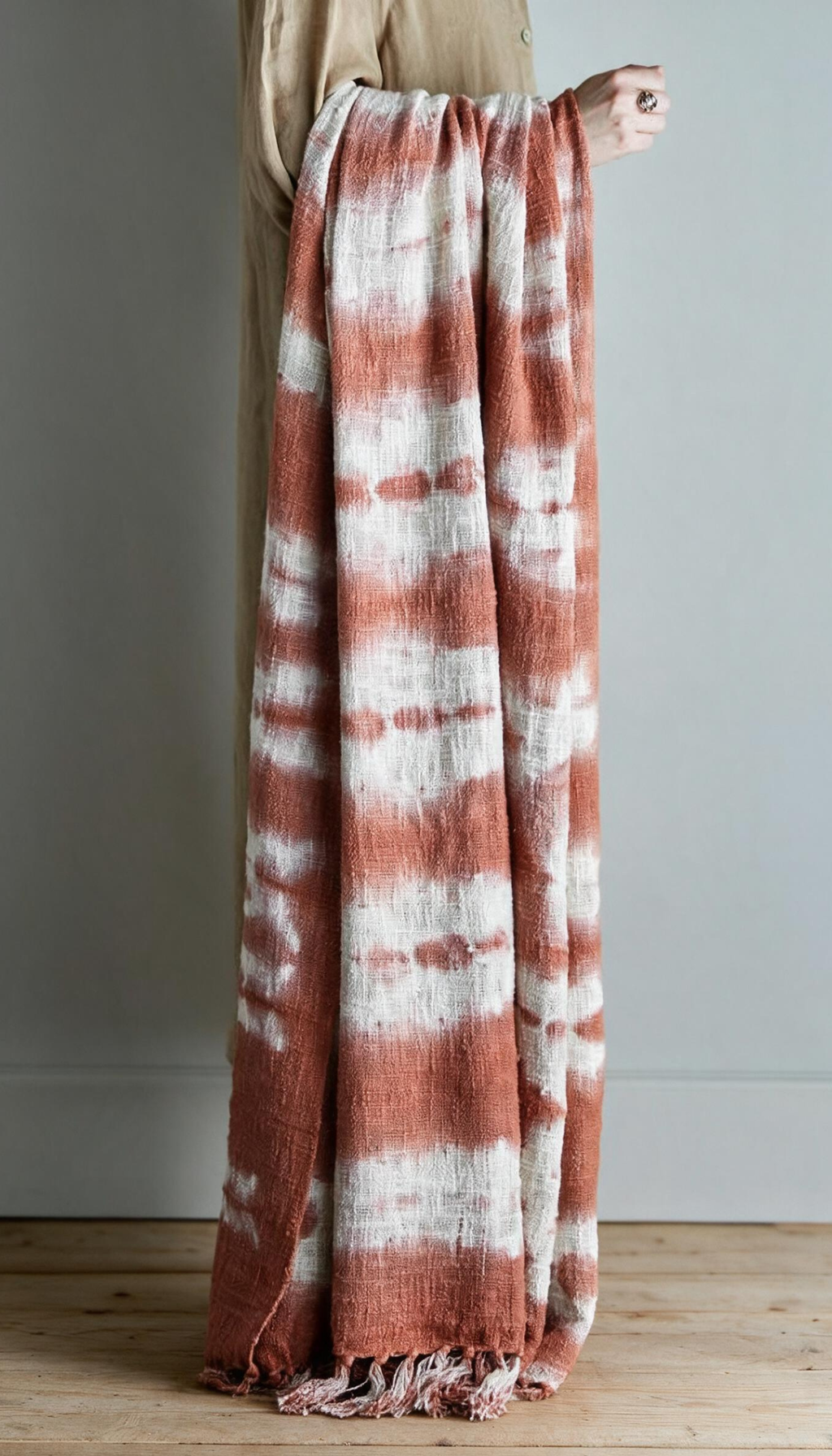 Manta de sofá modelo Salina doblada, con estampado orgánico de estilo boho en colores terracota y crema, mostrando su textura suave y acabado con flecos.