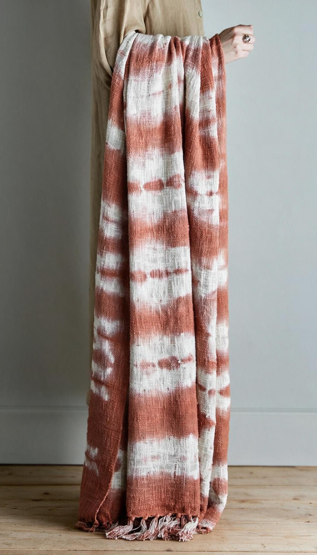 Manta de sofá modelo Salina doblada, con estampado orgánico de estilo boho en colores terracota y crema, mostrando su textura suave y acabado con flecos.
