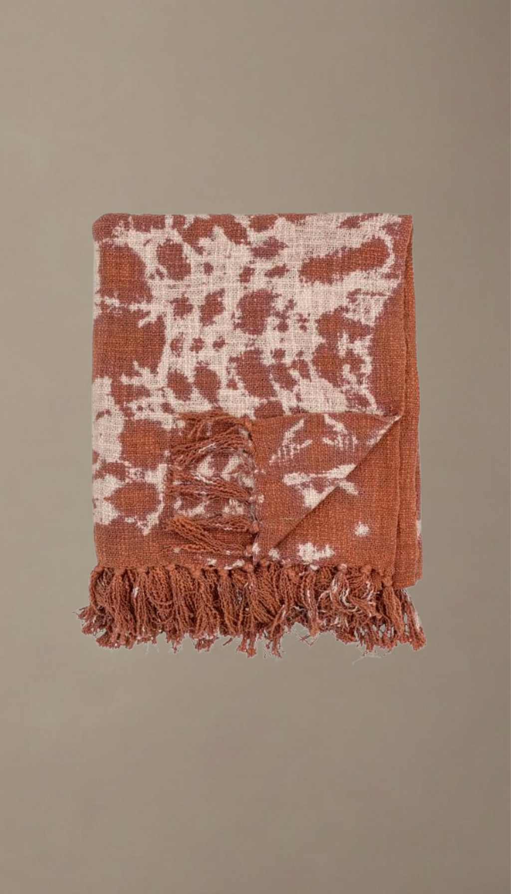 Manta de sofá modelo Salina doblada, con estampado orgánico de estilo boho en colores terracota y crema, mostrando su textura suave y acabado con flecos.