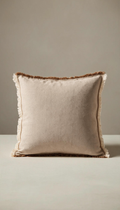 Funda de cojín cuadrada modelo Medina confeccionada en tejido natural color beige arena, rematada con flecos deshilachados a contraste en color marrón tierra, perteneciente a un pack de dos unidades.