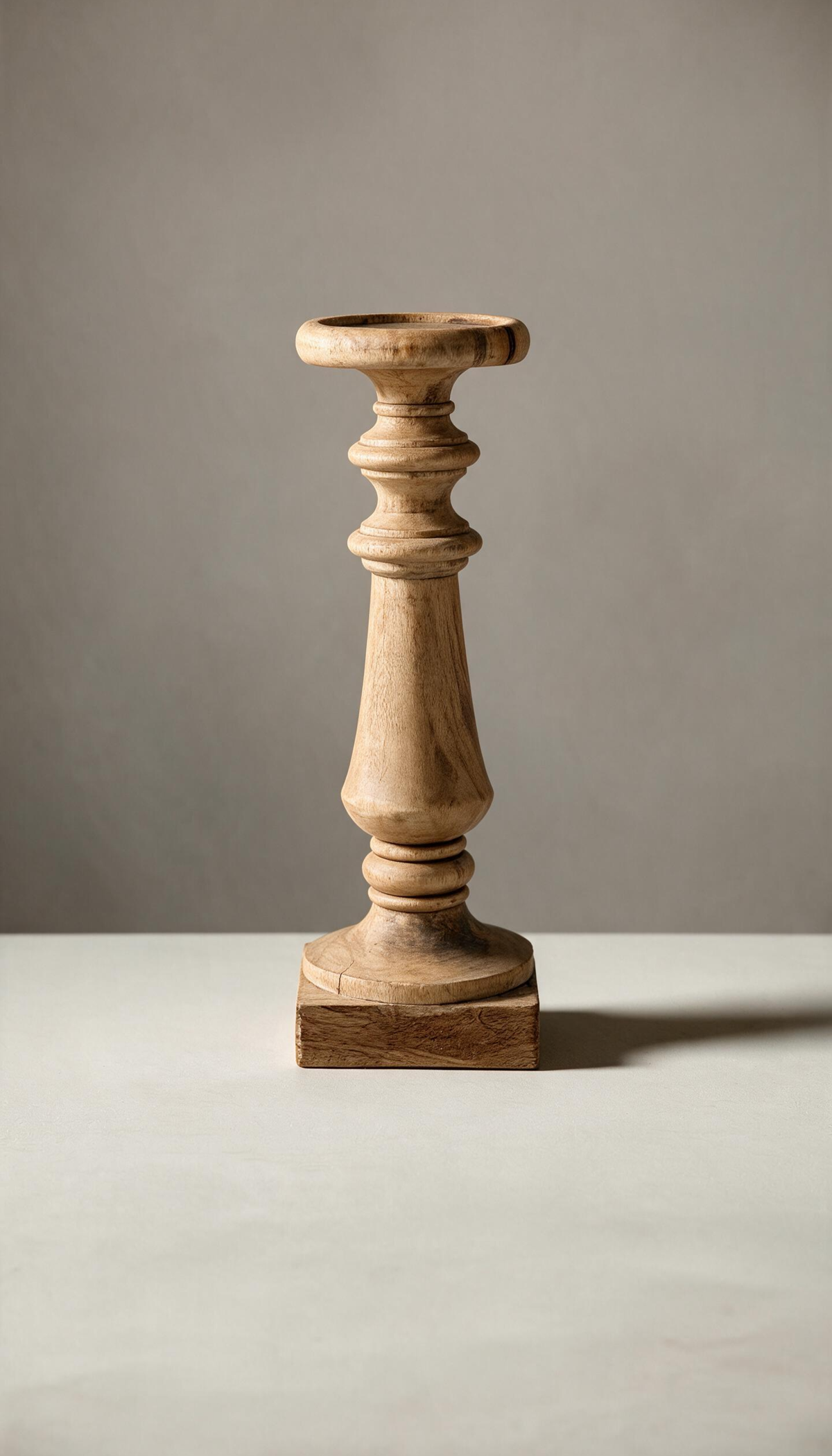 Pedestal de madera natural modelo Jara con diseño clásico torneado, base cuadrada y plato superior redondo, utilizado como portavelas de estilo rústico.