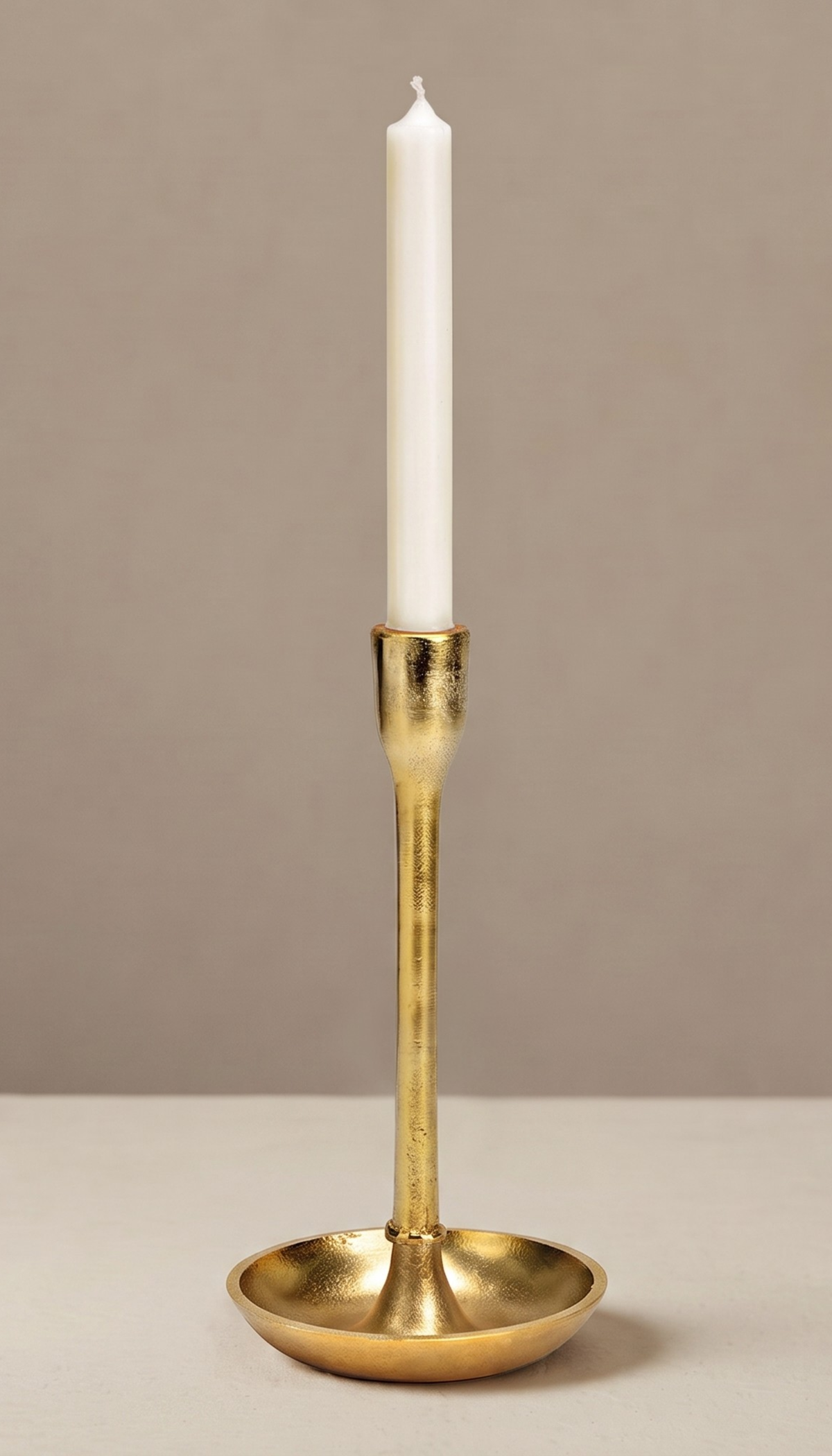 Portavelas de metal modelo Salina en color dorado, mostrando su silueta esbelta y minimalista con acabado texturizado de aspecto artesanal sobre una superficie despejada.