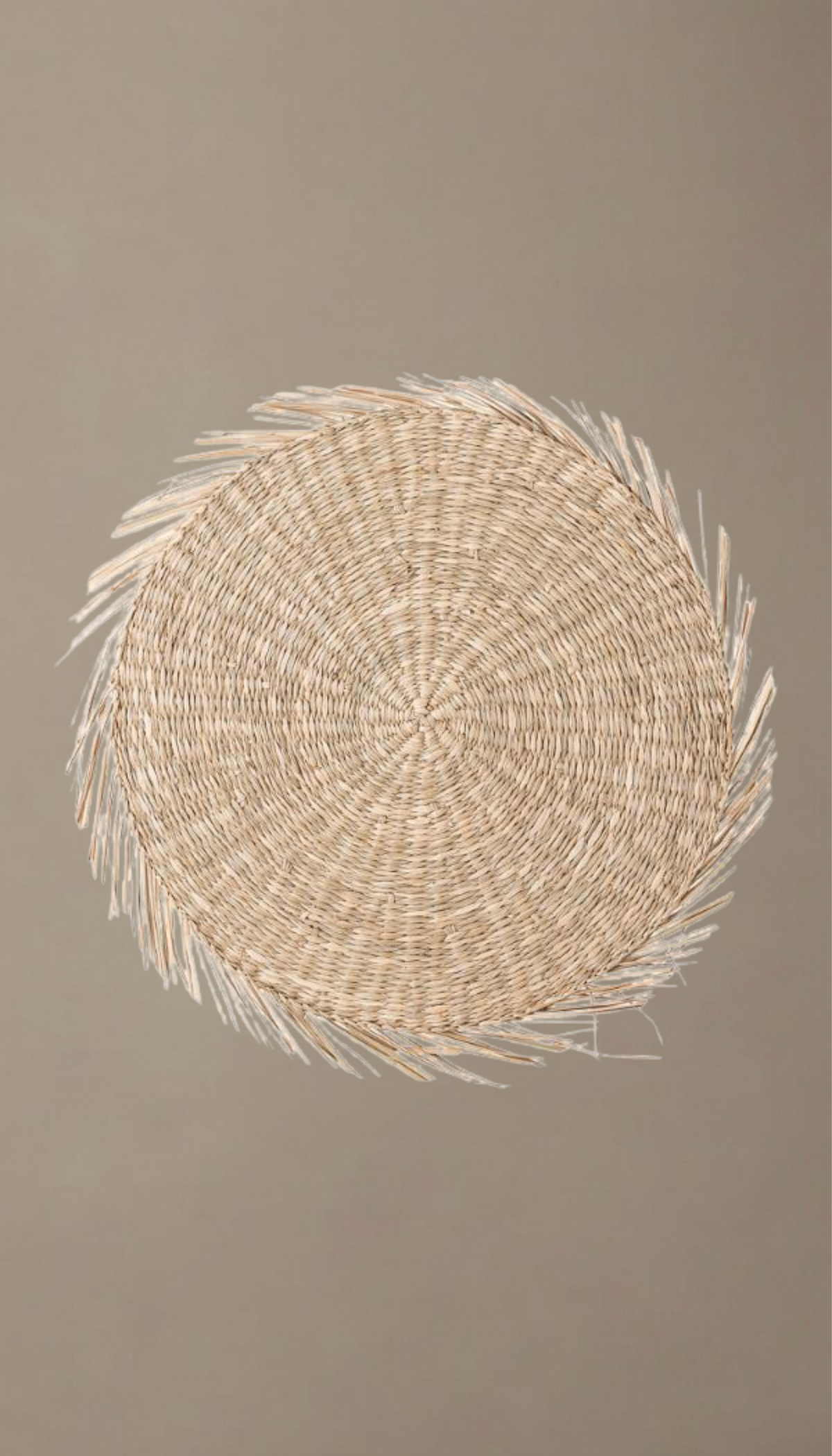 Salvamantel redondo modelo Priego visto desde arriba, trenzado en fibras naturales de seagrass con diseño en espiral y bordes terminados con flecos rústicos.