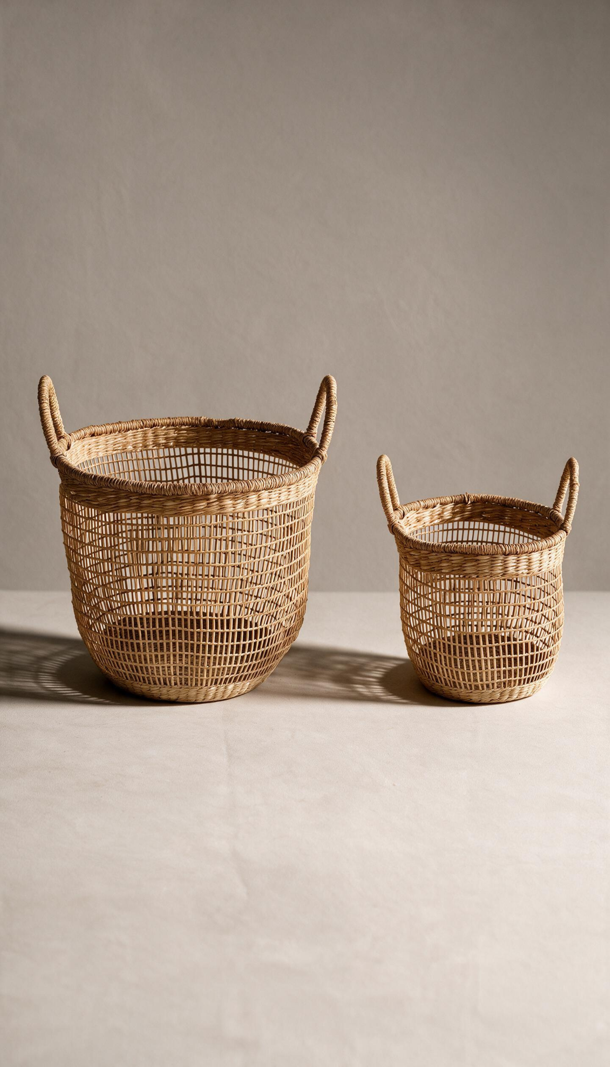 Cesta organizadora modelo Priego elaborada en fibras naturales con un diseño de trenzado abierto calado y dos asas superiores, proyectando una sombra sobre fondo neutro.