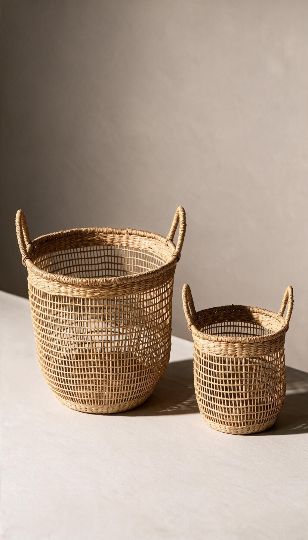 Cesta organizadora modelo Priego elaborada en fibras naturales con un diseño de trenzado abierto calado y dos asas superiores, proyectando una sombra sobre fondo neutro.