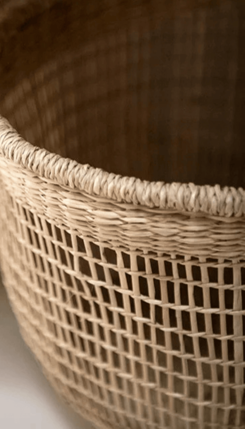 Cesta organizadora modelo Priego elaborada en fibras naturales con un diseño de trenzado abierto calado y dos asas superiores, proyectando una sombra sobre fondo neutro.