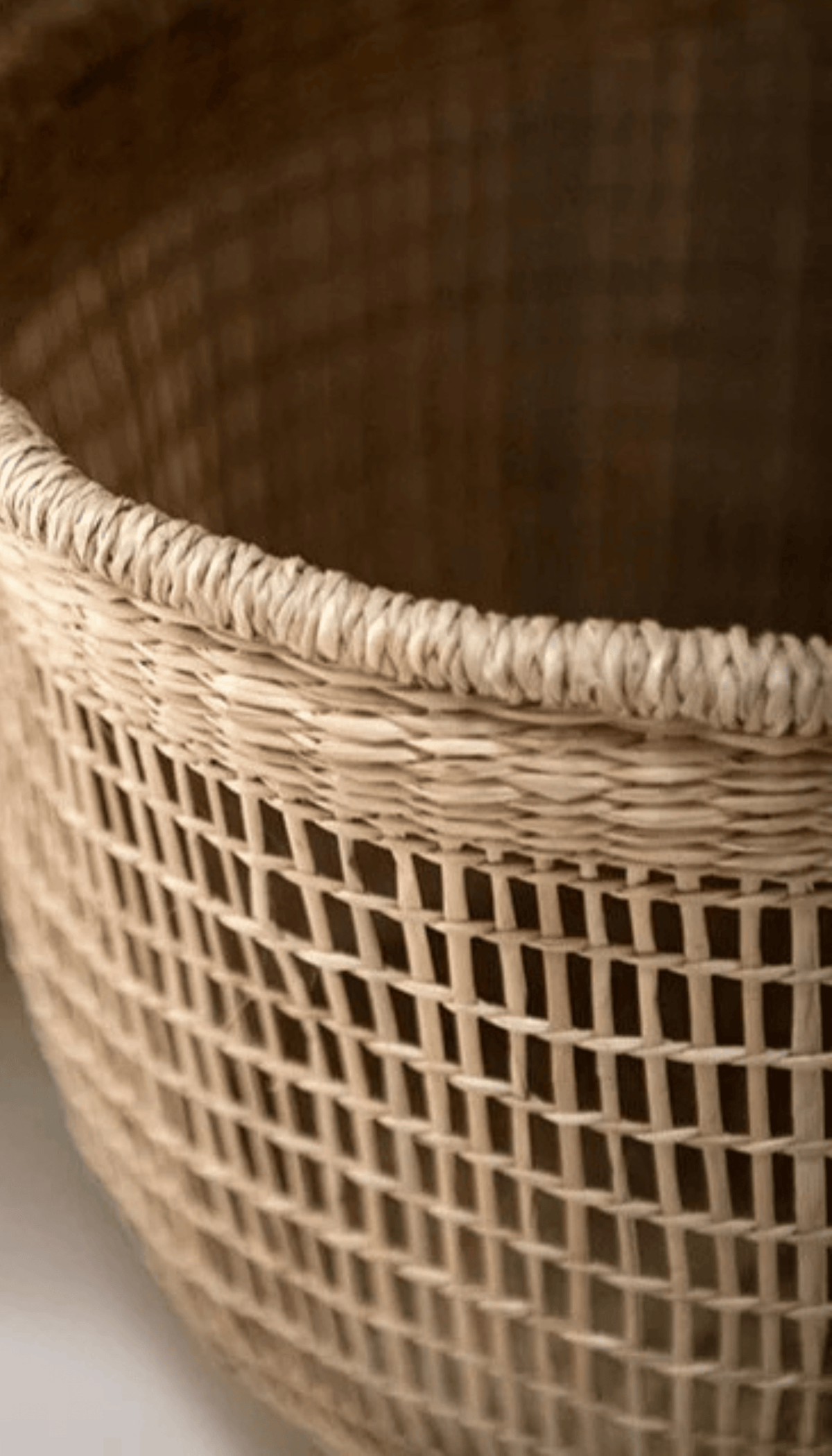 Cesta organizadora modelo Priego elaborada en fibras naturales con un diseño de trenzado abierto calado y dos asas superiores, proyectando una sombra sobre fondo neutro.