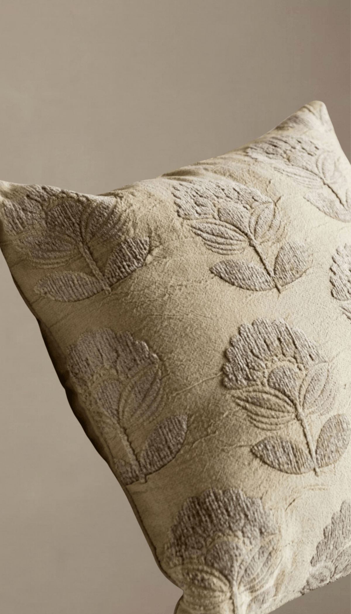 Cojín cuadrado de algodón modelo Vejer en color beige claro, decorado con un elegante patrón de flores clásicas bordadas en relieve tono sobre tono.