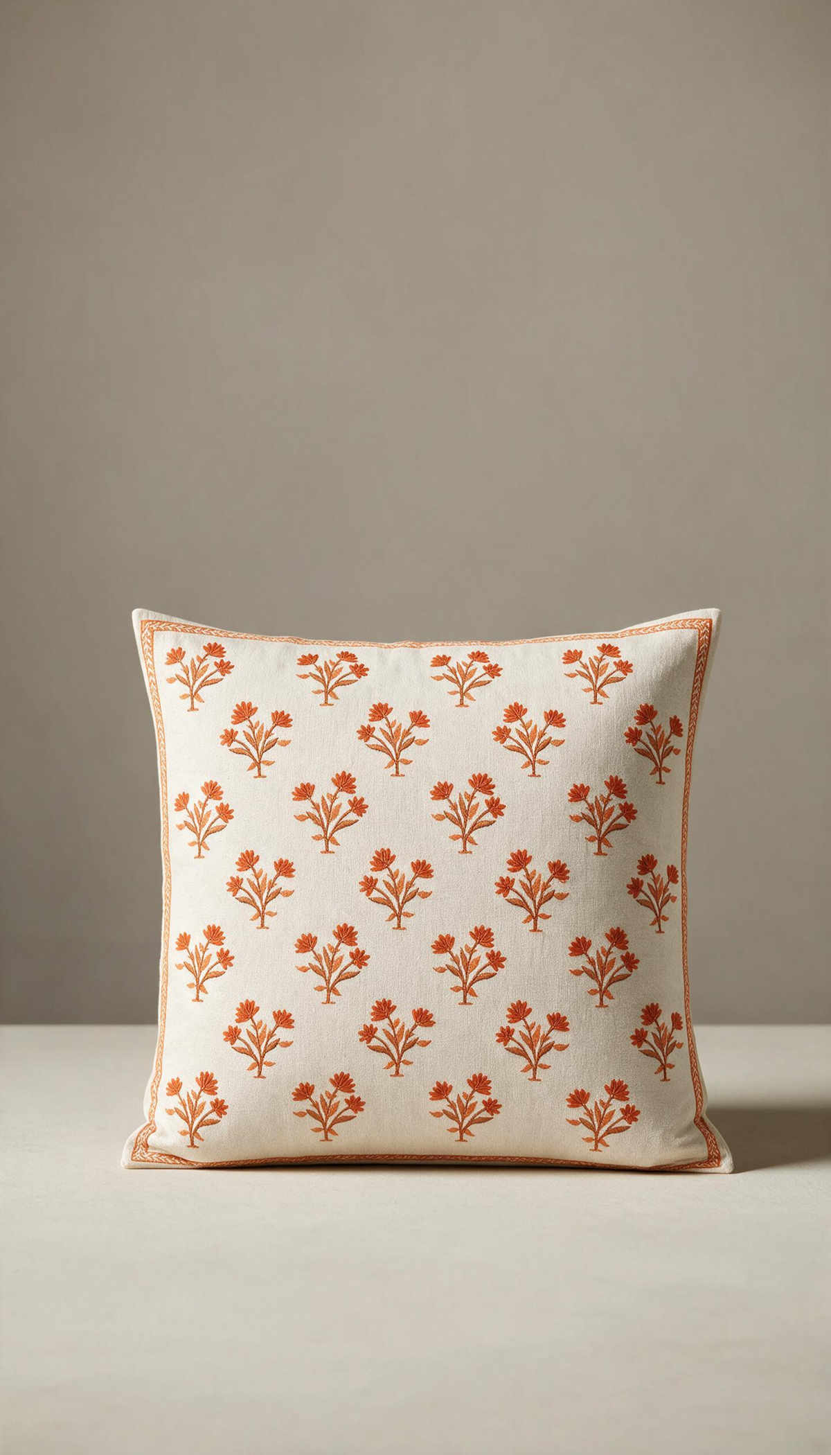 Funda de cojín cuadrado modelo Lentisco sobre una superficie clara, destacando su fondo crudo con un estampado floral repetitivo de estilo block print en color terracota y un fino marco a juego.